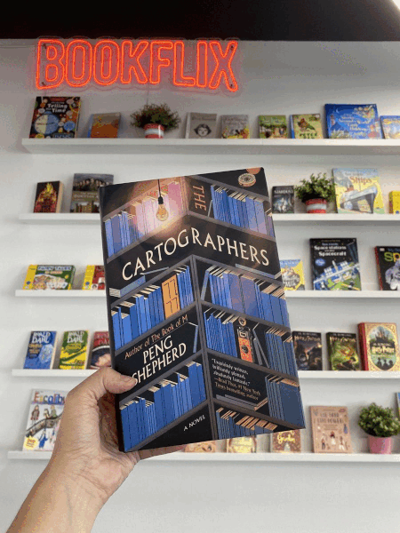 Книга The Cartographers на фоне полок Bookflix